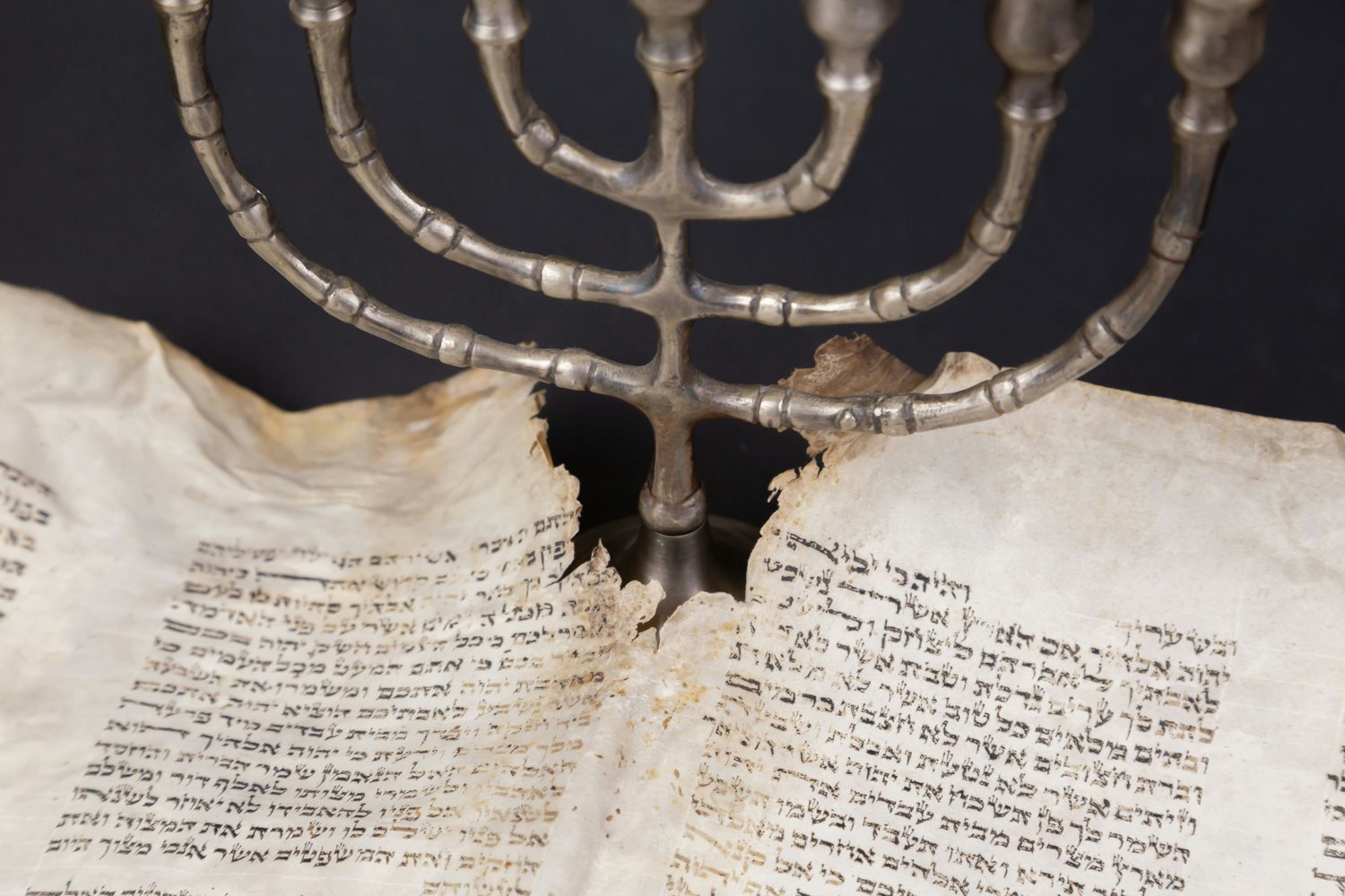 A menorah standing over an ancient parchment scroll